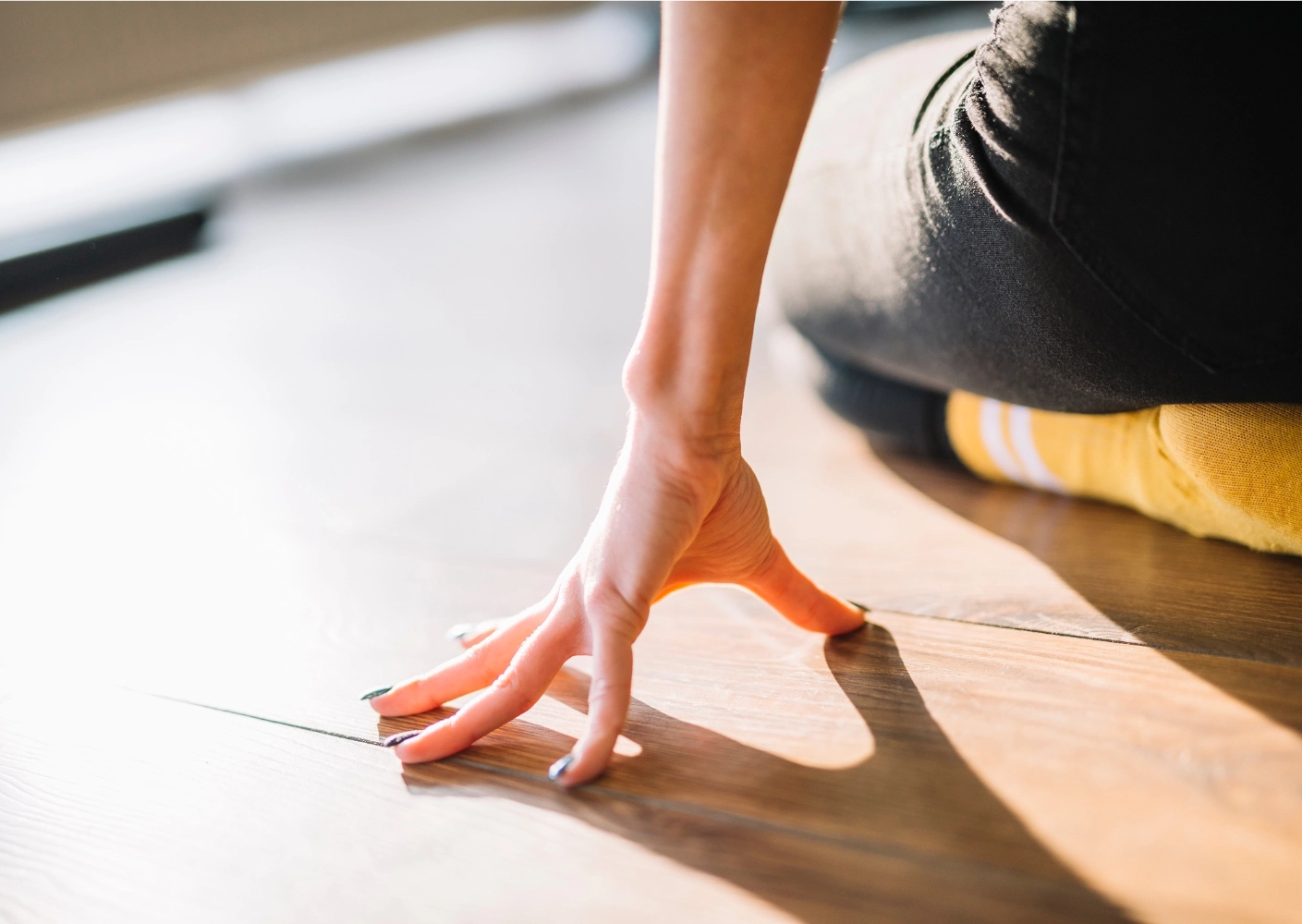 Person's hand touching a wooden floor