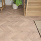 Wooden flooring with a herringbone pattern in a room setting.